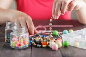 Woman’s hands making bracelete with plastic beads